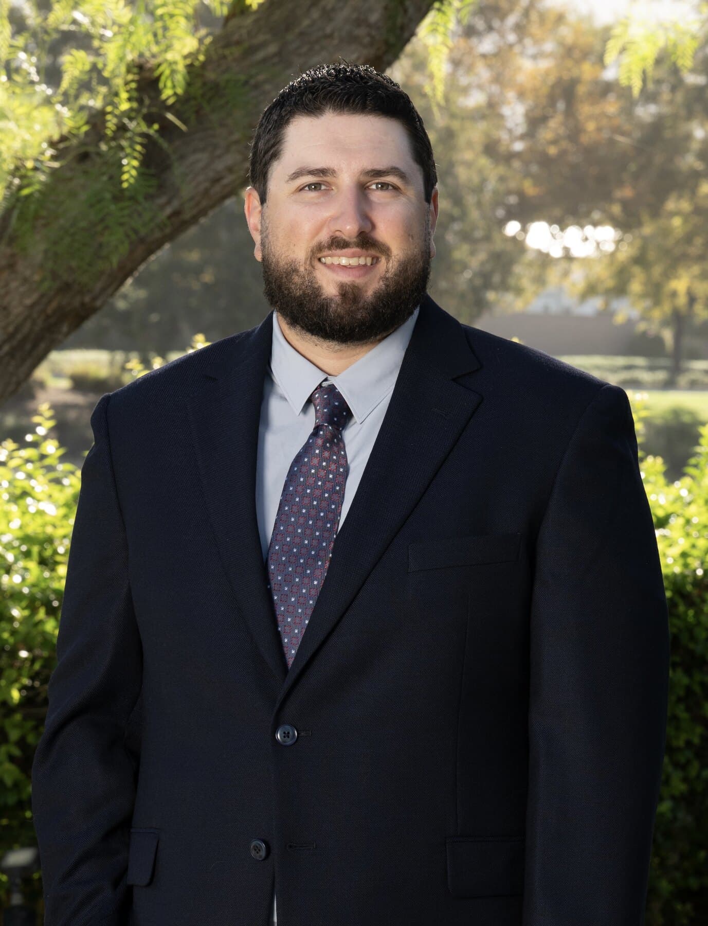 Frank Sandoval standing outdoors in a navy suit